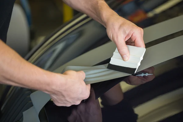 Car wrapper straightening foil with a squeegee — Stock Photo, Image