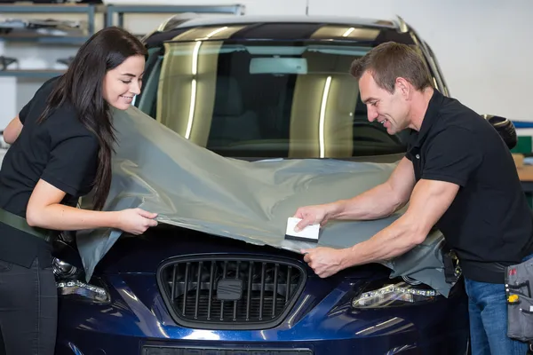 Car wrappers using squeegee to straighten vinyl film — Stock Photo, Image