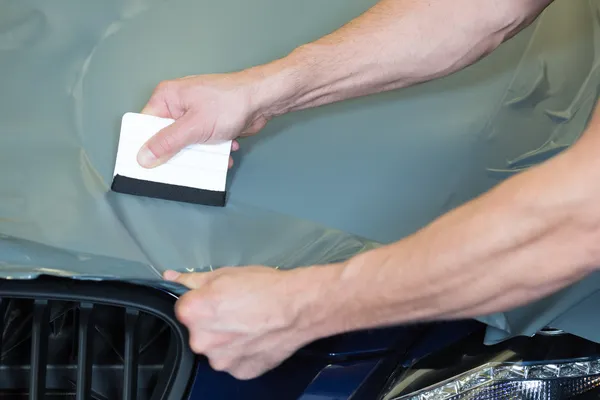 Car wrappers using squeegee to straighten vinyl film — Stock Photo, Image