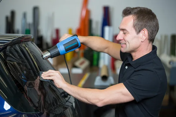 Auto wrapper met behulp van warmte pistool en squegee voor het verven van venster — Stockfoto