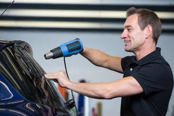 Autofolie mit Wärmepistole und Quietsche zum Färben der Scheibe — Stockfoto