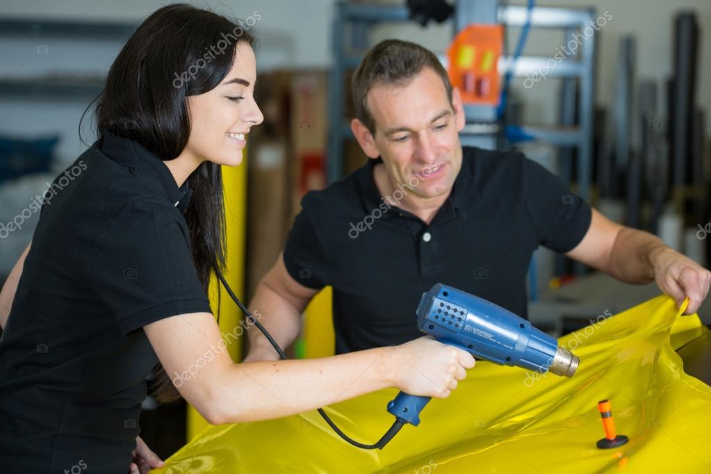 Car wrappers using heat gun to prepare vinyl foil — Stock Photo