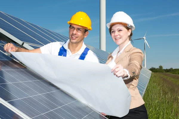 Ingénieurs photovoltaïques avec plan de construction aux panneaux solaires — Photo