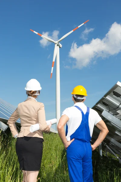 Engenheiro e empreiteiro posando na frente da turbina eólica — Fotografia de Stock