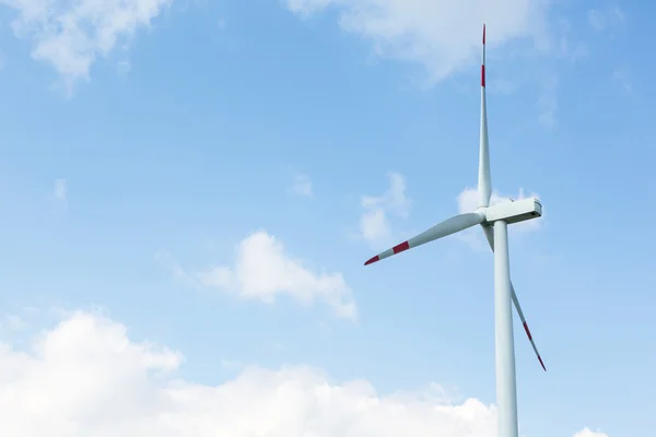 Uma turbina eólica na frente do céu azul com nuvens — Fotografia de Stock