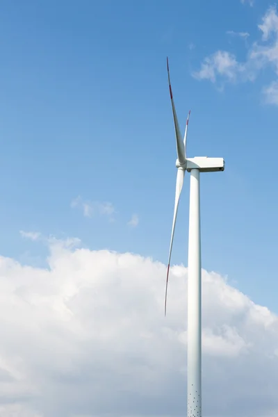 Uma turbina eólica na frente do céu azul com nuvens — Fotografia de Stock