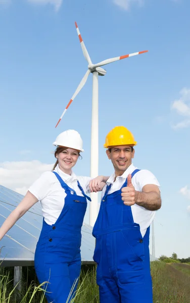 Dos ingenieros posando con turbina eólica y paneles solares — Foto de Stock