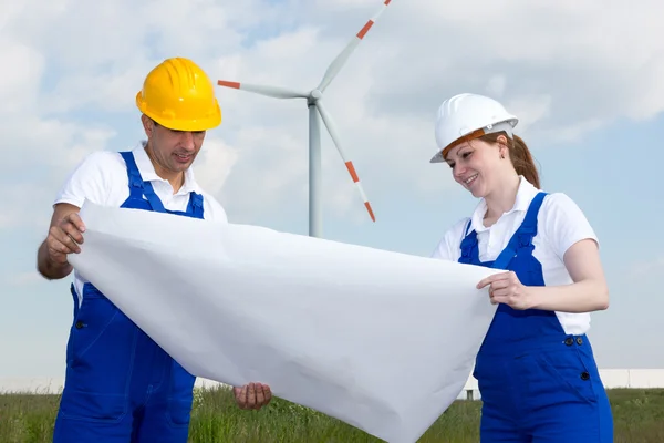 Engineers with construction plan in wind farm — 图库照片