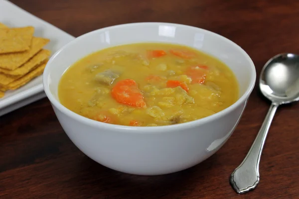Жовтий Vegan/Вегетаріанський розділити гороховий суп з крекерами і ложка — стокове фото