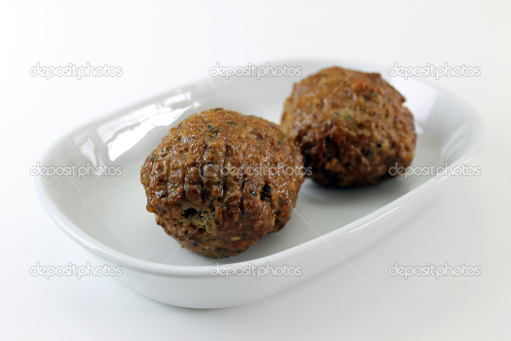 Two meatballs angled on a plate closeup