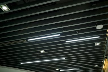 Ventilation and air conditioning system in industrial, exhibition hall or commercial premises with lighting, under the ceiling. Ventilation pipes and hoods.