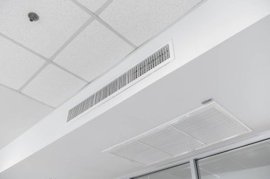 Tavana monte edilmiş kaset tipi klima ve beyaz tavanda modern lamba ışığı. Ev ya da ofis için havalandırma kanalı