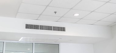 Tavana monte edilmiş kaset tipi klima ve beyaz tavanda modern lamba ışığı. Ev ya da ofis için havalandırma kanalı