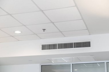 Tavana monte edilmiş kaset tipi klima ve beyaz tavanda modern lamba ışığı. Ev ya da ofis için havalandırma kanalı