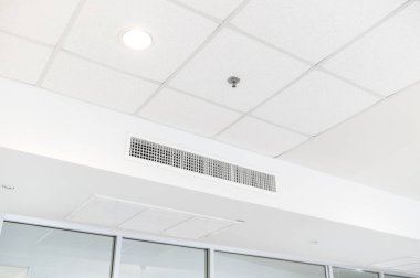 Tavana monte edilmiş kaset tipi klima ve beyaz tavanda modern lamba ışığı. Ev ya da ofis için havalandırma kanalı