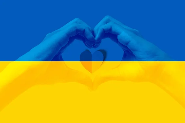 Man hands making a heart shape with Ukraine flag color background. Stay with ukraine symbol. Hand heart love gesture with ukrainian flag background.