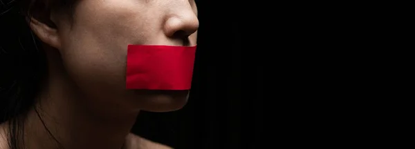 Concept on the topic of freedom of speech, censorship, freedom of press. International Human Right day: the girl\'s face is sealed her mouth with red paper