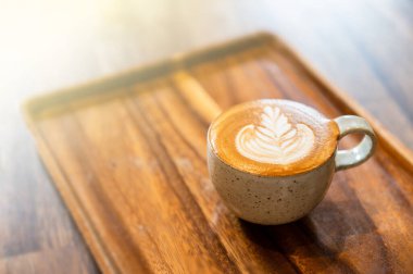 Kahve seramik bardakta, kafenin ahşap masasında, ışıklandırma arka planında..