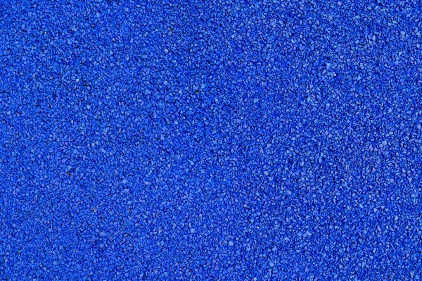 Plastik yumuşak kaplama dokusuna yakın çekim. Spor stadyumunda kullanılan yüzey, koşu pisti, koşu bandı, çocuk parkı. Geri dönüşümlü lastiklerden yapılmış modern zemin tanecikleri..