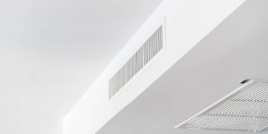 Tavana monte edilmiş kaset tipi klima ve beyaz tavanda modern lamba ışığı. Ev ya da ofis için havalandırma kanalı