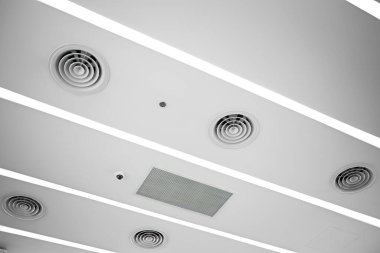 Tavana monte edilmiş kaset tipi klima ve beyaz tavanda modern lamba ışığı. Ev ya da ofis için havalandırma kanalı.