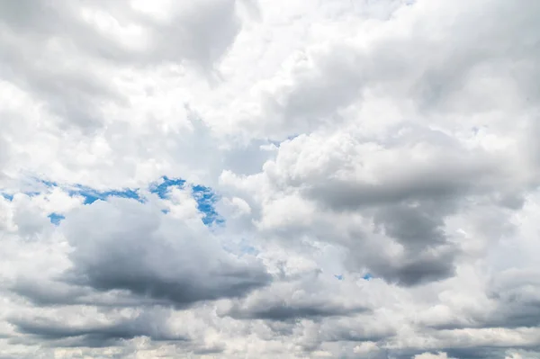 Storm clouds floating in a rainy day with natural light. Cloudscape scenery, overcast weather above blue sky. White and grey clouds scenic nature environment background.