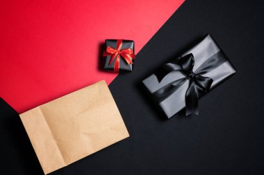 Kırmızı, alışveriş çantası, siyah kurdeleler ve kırmızı ve siyah arka planda izole edilmiş kumbara hediye kutusunun üst görüntüsü. Alışveriş konsepti boks günü ve Kara Cuma indirimli kompozisyon.