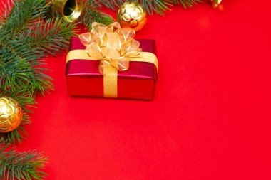 Noel konsepti. Noel hediyesi kutusunun üst manzarası ladin dalları ve kırmızı zili olan altın toplar..