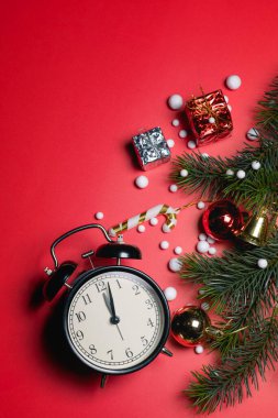 Noel konsepti. Noel hediyesi kutusunun üst görüntüsü ladin dalları, kırmızı arka planda saat ve çan olan renkli toplar.