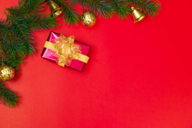 Noel konsepti. Noel hediyesi kutusunun üst manzarası ladin dalları ve kırmızı zili olan altın toplar..