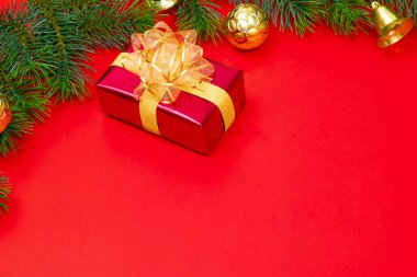 Noel konsepti. Noel hediyesi kutusunun üst manzarası ladin dalları ve kırmızı zili olan altın toplar..