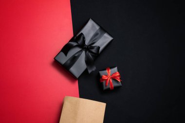 Kırmızı, alışveriş çantası, siyah kurdeleler ve kırmızı ve siyah arka planda izole edilmiş kumbara hediye kutusunun üst görüntüsü. Alışveriş konsepti boks günü ve Kara Cuma indirimli kompozisyon.