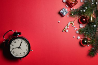 Noel konsepti. Noel hediyesi kutusunun üst görüntüsü ladin dalları, kırmızı arka planda saat ve çan olan renkli toplar.