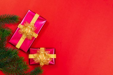Noel konsepti. Noel hediyesi kutusunun üst manzarası ladin dalları ve kırmızı zili olan altın toplar..