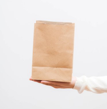Paketleme şablonu maketi. Teslimat hizmeti konsepti. Uzayı kopyala Reklam alanı afişi. Kadın, beyaz arka planda kahverengi, boş, boş, eko kağıt torba tutuyor..