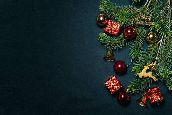 Christmas background concept. Top view of Christmas gift box colorful balls with spruce branches and bell on black background.