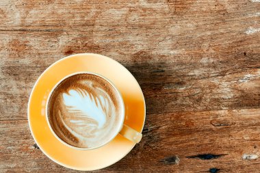 Eski ahşap masadaki latte sanat kahvesi manzarası..