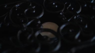 Small candle in a cast iron stand. Close-up of lighting a candle with a match. Warm beautiful fire. Cozy atmosphere.