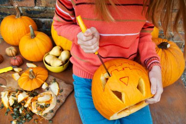 Kız masaya oturuyor ve balkabağı canavarını oyuyor. Cadılar Bayramı 'nı kutlayalım. Bir kriko feneri yap.. 