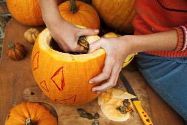 Bir el olgun bir balkabağından kabak çekirdeğini çıkarır. Cadılar Bayramı ya da Şükran Günü için balkabağı dekoru yap.. 
