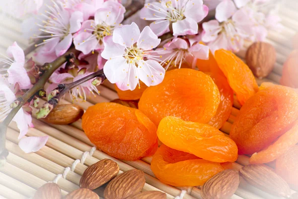 Dried apricots with almonds and blossoming branch on bamboo napk