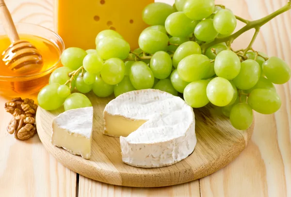Stilleven van druiven, kaas, honing en walnoten — Stockfoto