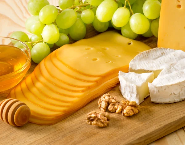 Натюрморт из сыра, меда, грецких орехов и винограда — стоковое фото