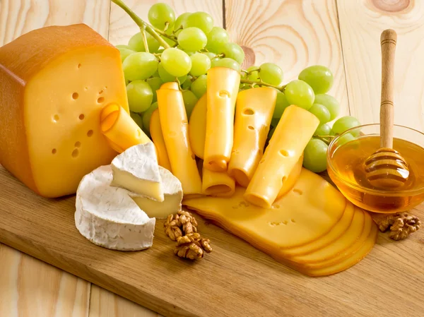 Still life of cheese, honey, walnuts and grapes — Stock Photo, Image
