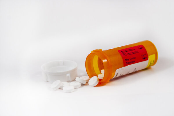 Бутылка для таблеток и таблетки на белом фоне
