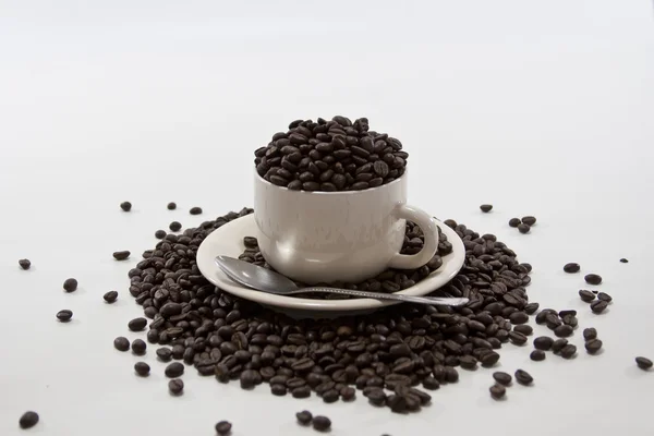 Grains de café débordent tasse de café sur fond blanc isolé — Photo