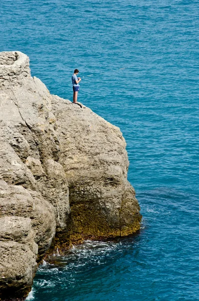 Boy fishing on a rock at the Sea — Stock Photo, Image