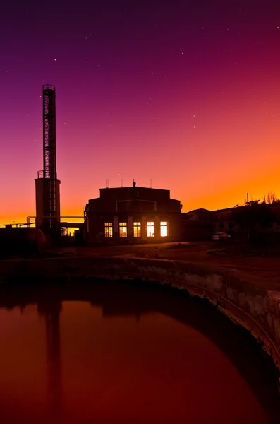Färgstark solnedgång bakom en industribyggnad — Stockfoto