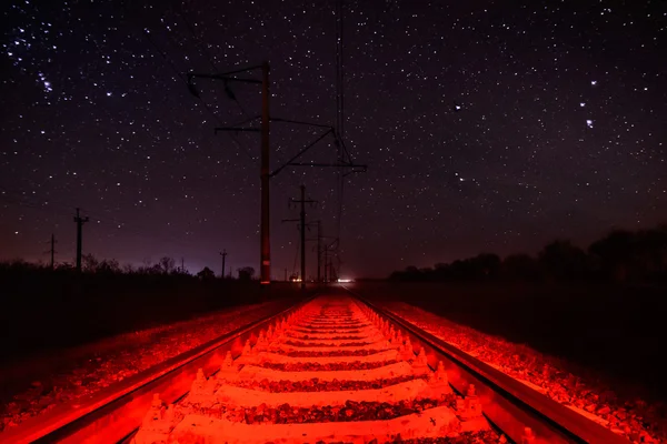 Рельсы на фоне звездного неба с необычной красной подсветкой — стоковое фото