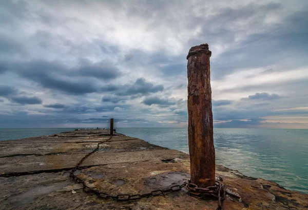 Oude concrete pier met roestig geketende Polen — Stockfoto